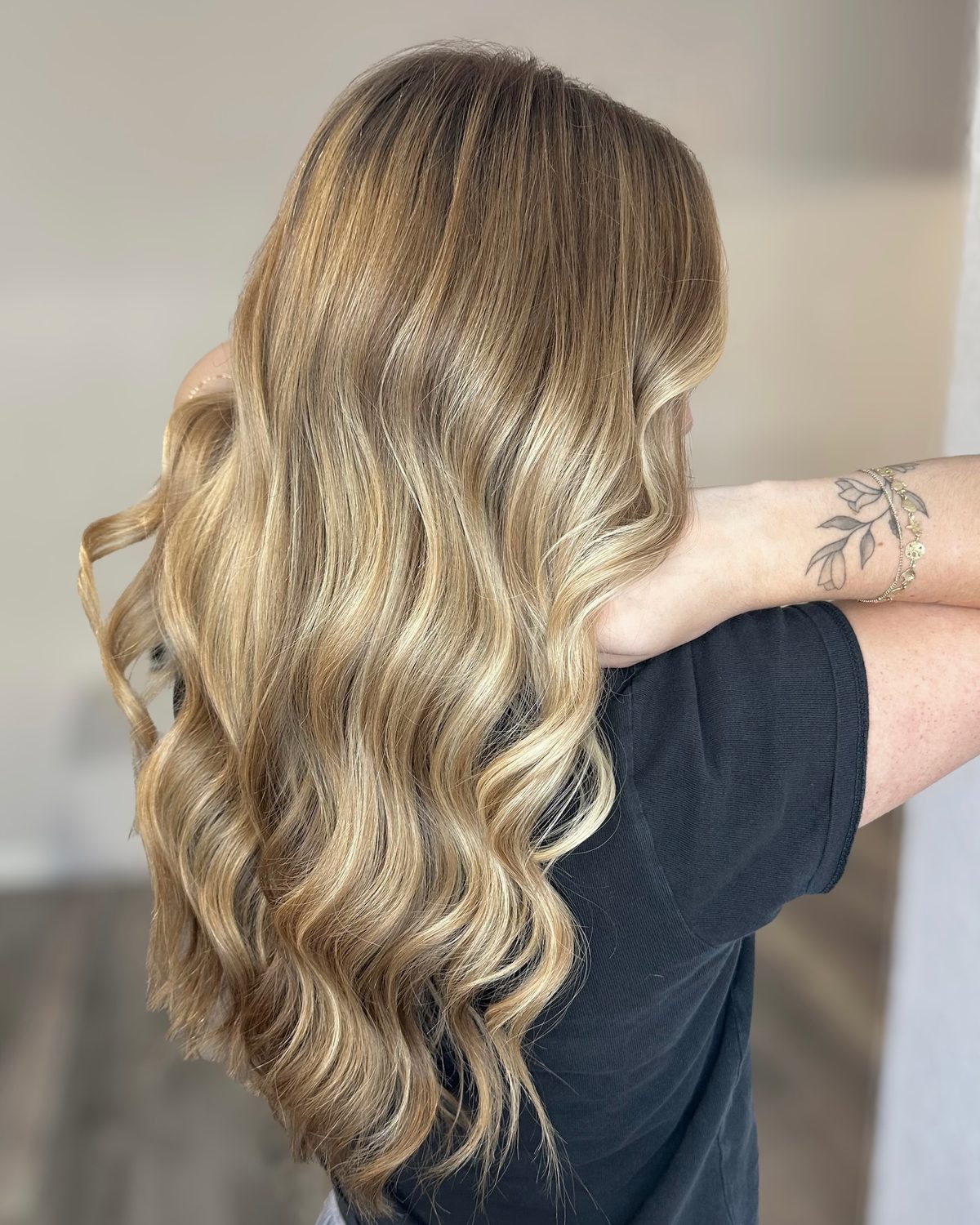 Back view of long, lived-in golden blonde balayage styled in loose waves